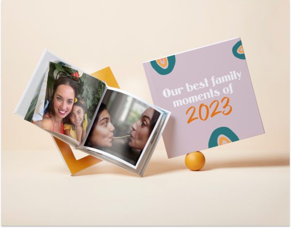 Two Square Hardcover Photo Books, one open to a page with family photos and one with a cover reading 