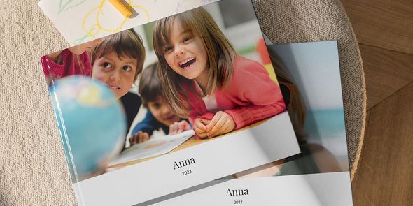 to fotobøker som sitter oppå hverandre. Den øverste boken viser et barn som smiler på skolen