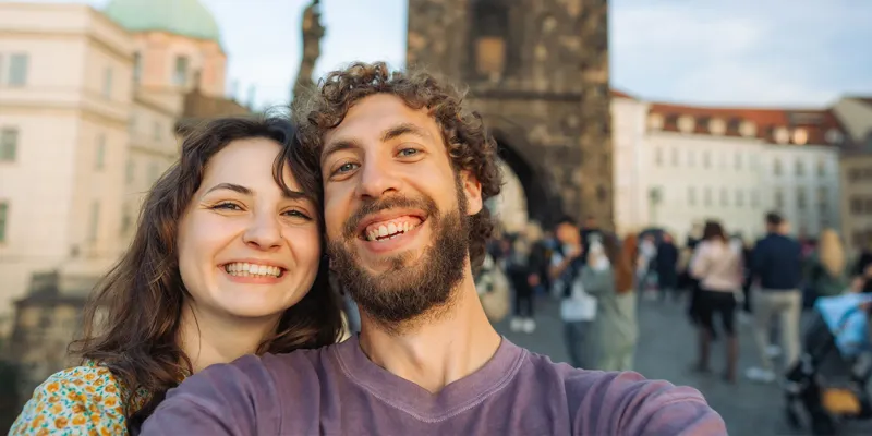 A couple taking a selfie on Charles Bridge in Prague, Czech Republic, capturing the romance of one of Europe’s most enchanting city breaks.