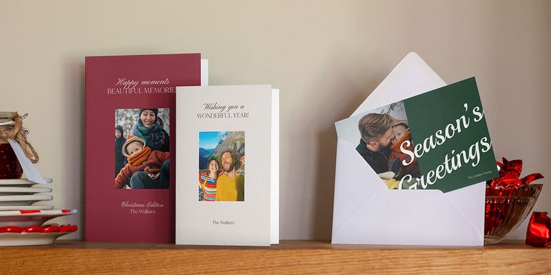 Burgundy, grey and green photo cards on a wooden shelf, one in a white envelope
