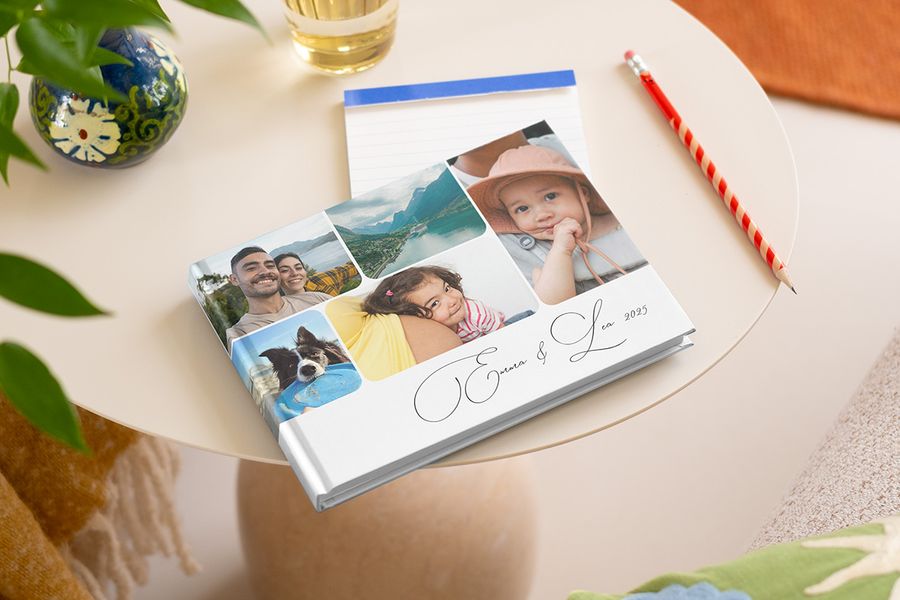 A 2025 one year photo book on a table, featuring a collage of multiple family yearbook pictures on the front cover.