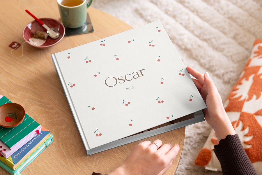 A woman about to open a my first photo book from Photobox on a wooden coffee table.