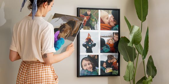 Personalised wall art ideas from Photobox, showing a woman admiring a framed photo collage of family pictures on a wall.