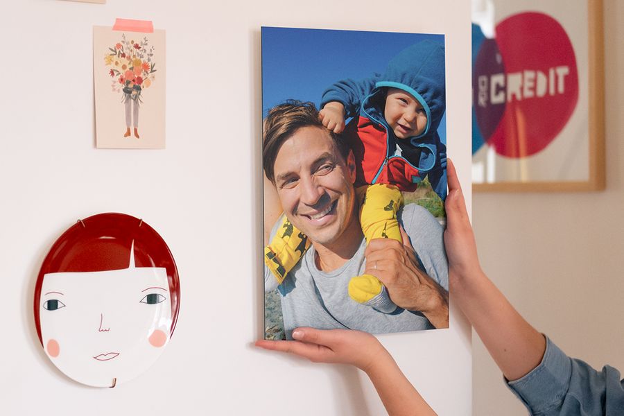 Someone hanging a personalised poster print of a father and baby as part of their wall frame decor.