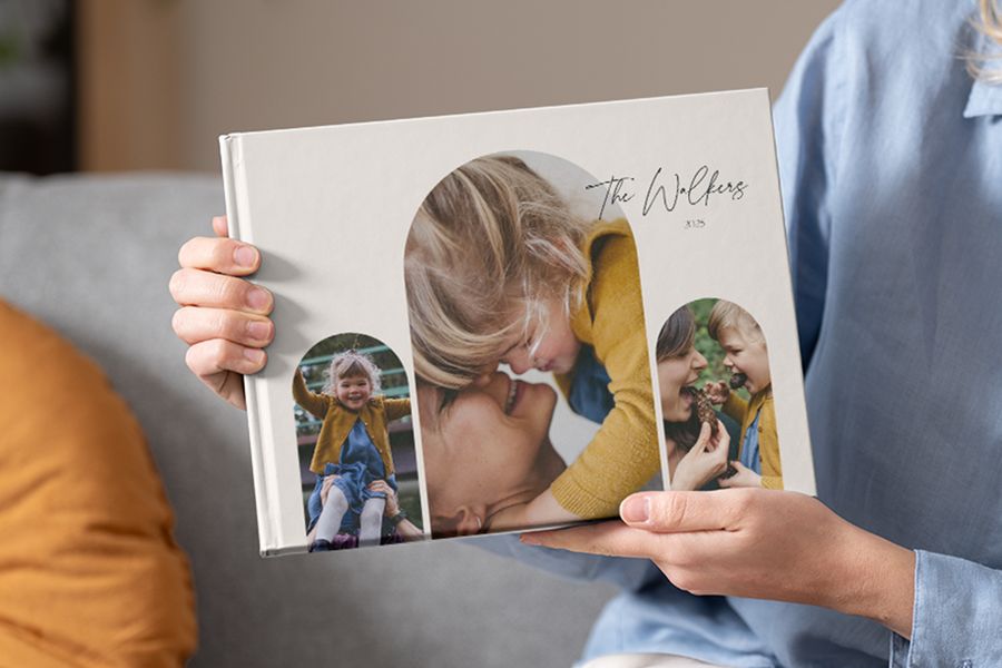 A family photo album being held, featuring several photos on the front cover, perfect for including sentimental photo album quotes and photobook quotes.
