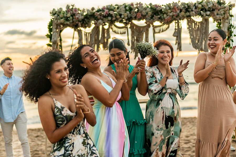 A candid beach wedding shot of smiling guests laughing, reflecting the anti-pose paparazzi aesthetic and current wedding photography trends with Photobox.