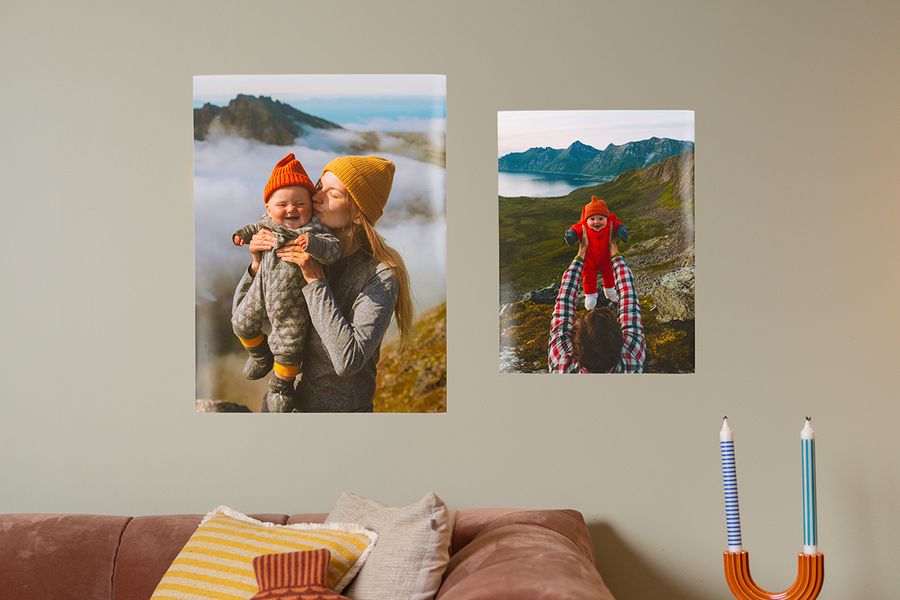 Two family posters, one featuring a mother and baby and the other just a baby, hanging above a sofa using picture hanging strips and poster strips from Photobox.