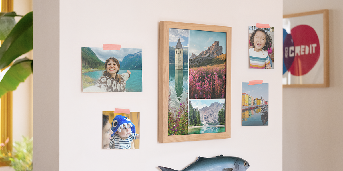 Photobox photo prints displayed on a wall in a home, with a large frame filled with landscape prints and four individual family photo prints, inspiring photo printing ideas and ways to print photos online.