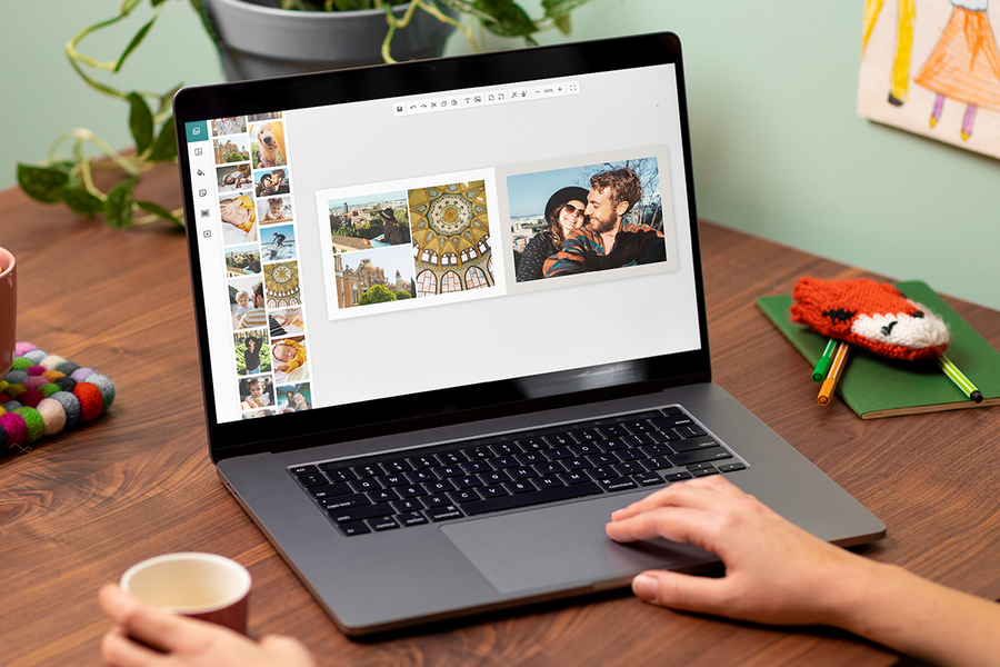 Someone using the Photobox editor on a laptop at a table to create a personalised product, inspiring an online photo book maker and quick and easy photo books.