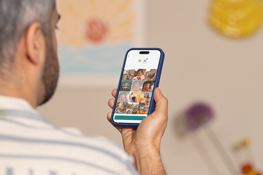 Someone using the Photobox Mobile App on their phone to create a personalised photo product, inspiring an online photo book maker and quick and easy photo books on the go.