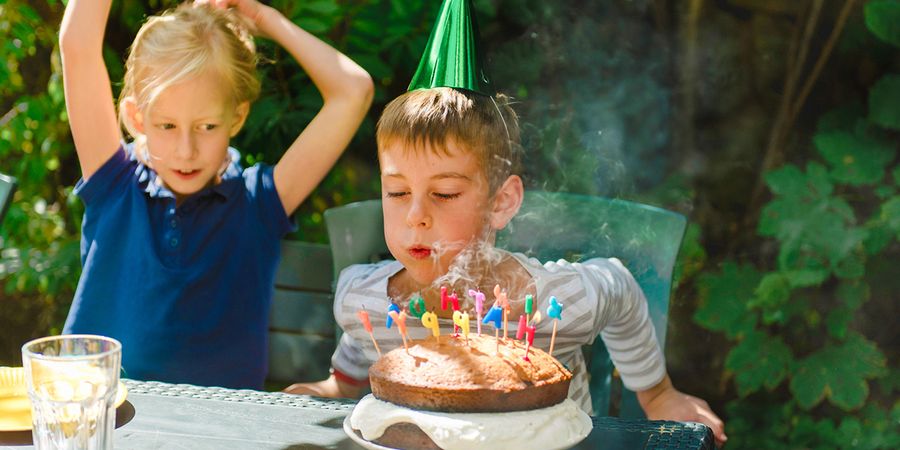 A boy blowing out candles on his birthday cake, inspiring Photobox children’s birthday party ideas and children’s party celebrations.
