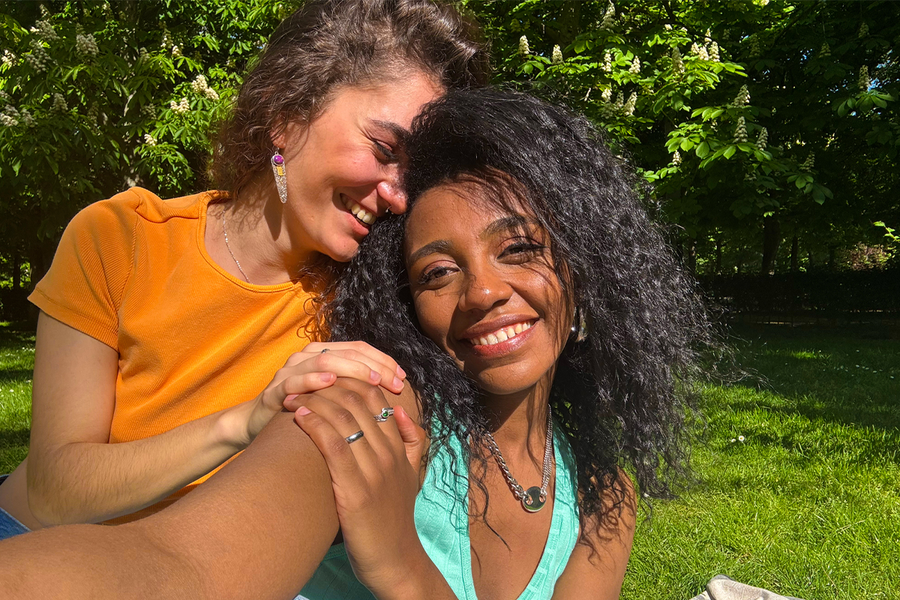 Two women smiling and taking a selfie in a lush green park, illustrating how bright colours can make sunlight photos feel vivid and full of life.