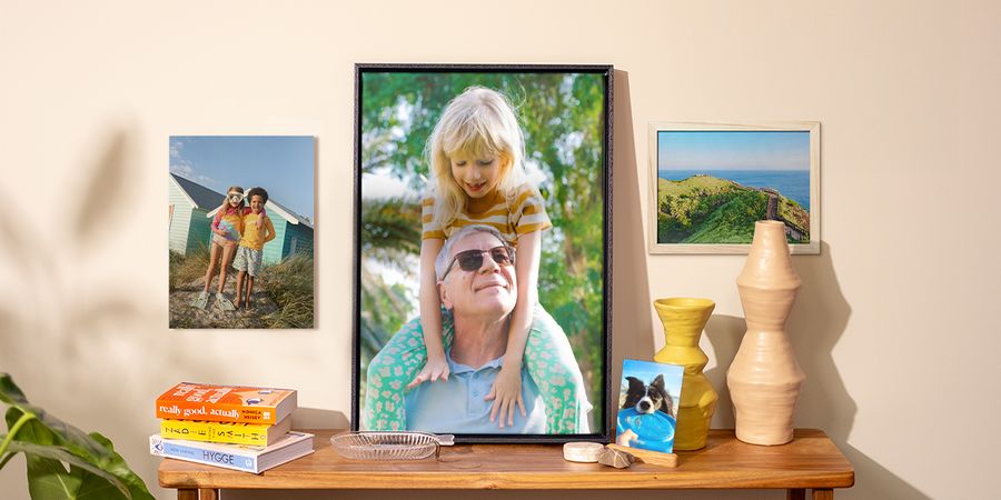 A selection of Photobox photo prints displayed around the home, including a dog photo print on a side table, a wall poster of children and two framed photo prints, inspiring photo prints for walls and spring home decor.
