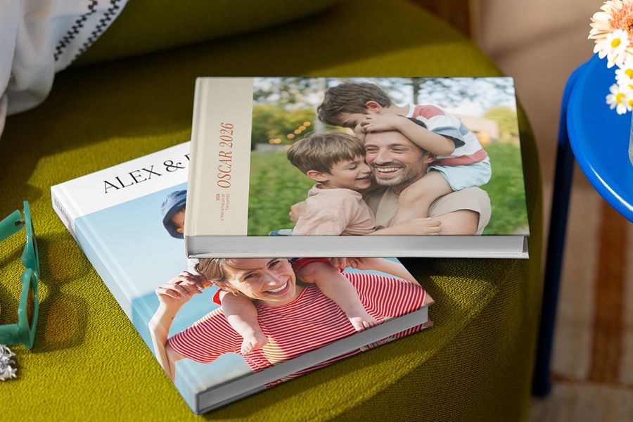 Two different Photobox holiday photo books with family images on the covers, showing parents, children, names and the year, illustrating best practices for creating a personalised travel photo book.