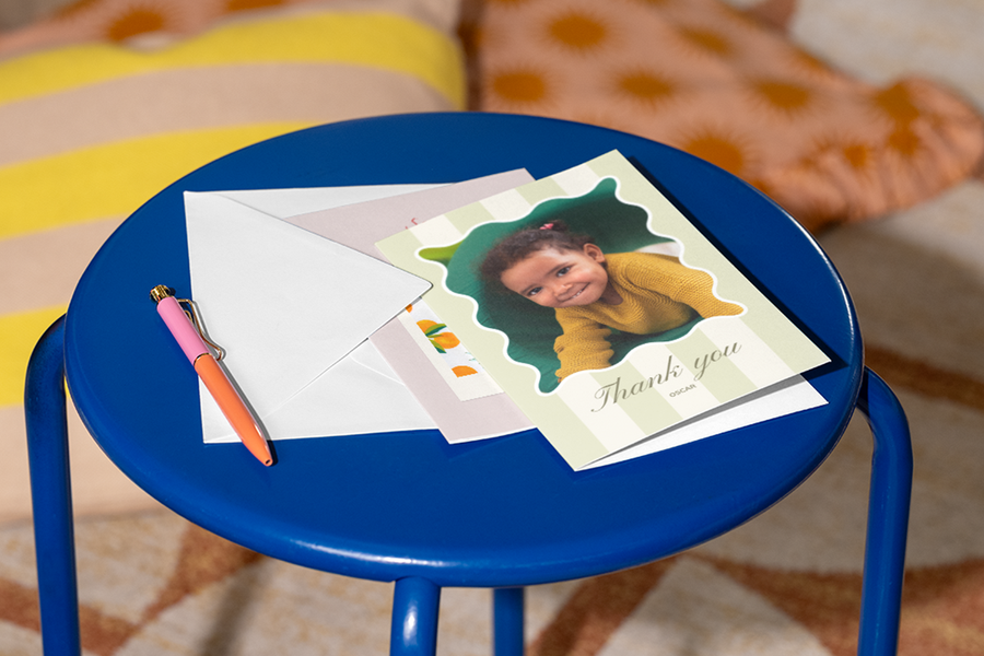 A personalised Photobox thank you teacher card with a photo of a little girl on the front sits on a stool with a pen beside it, inspiring what to write in a thank you teacher card with a warm and respectful message.