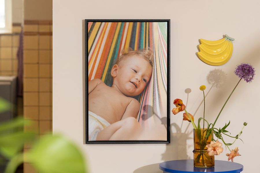 A piece of personalised Photobox wall art showing a baby next to flowers and fruit decor, inspiring bright and playful home decor for summer.