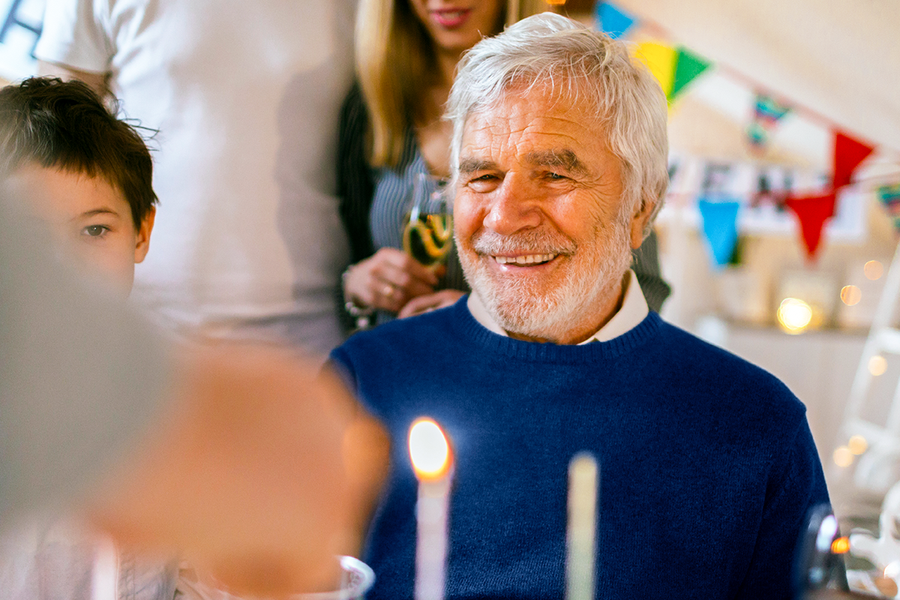 A grandfather smiling at his birthday celebration, illustrating 70th birthday gift ideas and birthday gifts for him from Photobox.