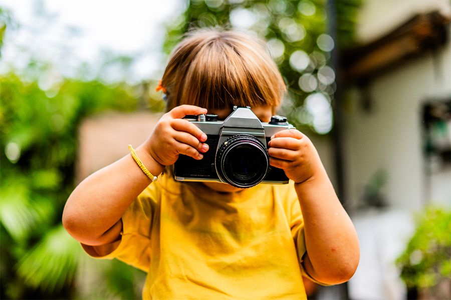 A young girl takes pictures with a camera, reflecting Photobox's creative staycation ideas.