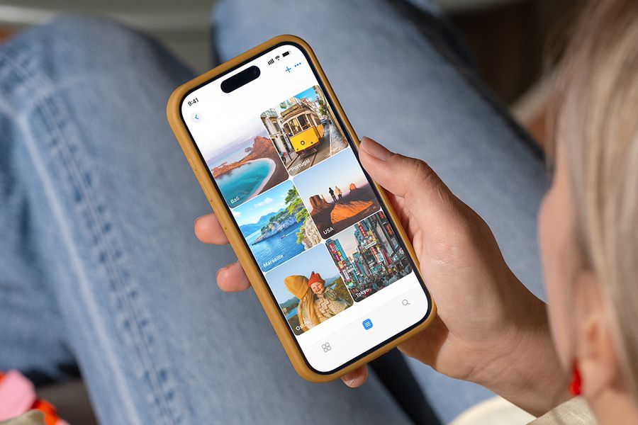 A person looks at photo folders on their phone named after holiday destinations like 'Bali' and 'Tokyo', illustrating Photobox's tips for organising photos ready for printing.