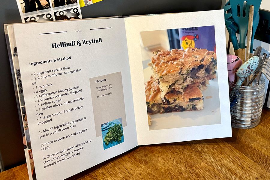 An open personalised recipe book sits in a kitchen setting, with a jar of spoons and cooking utensils in the background, illustrating Photobox's tips for choosing which recipes to include before creating your own recipe book.