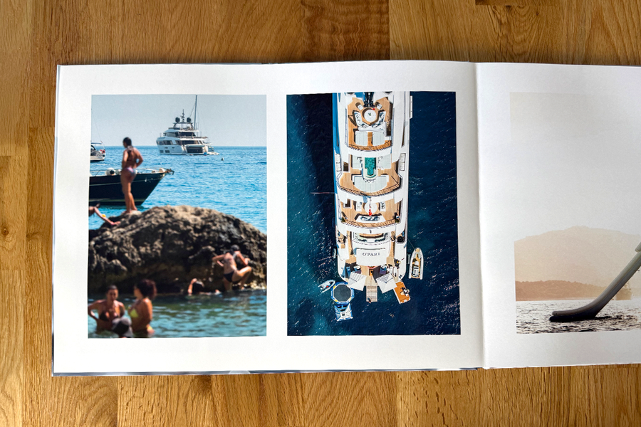 An open spread from Charl van Rooy's photo book shows holiday beach scenes, including people relaxing by the sea and a yacht, illustrating the visual flow of his photography portfolio.
