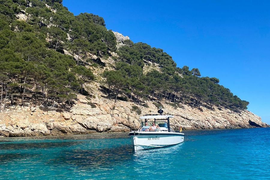 A couple sits on a boat beside a beautiful rugged coastline in Ibiza, capturing the quieter, laid-back side of a September holiday on the island.