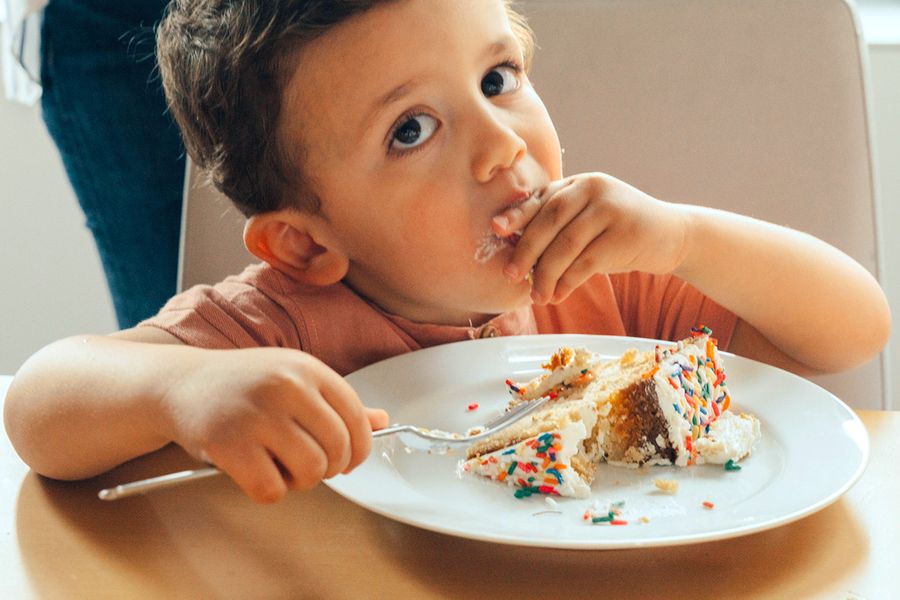 A little boy eats birthday cake, illustrating Photobox's photo checklist for capturing the best kids' birthday party moments.