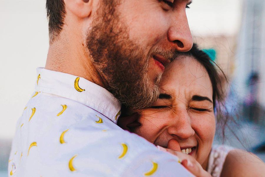 A couple embraces, with the woman smiling and her eyes closed, illustrating Photobox's ideas for what to write in an anniversary card.