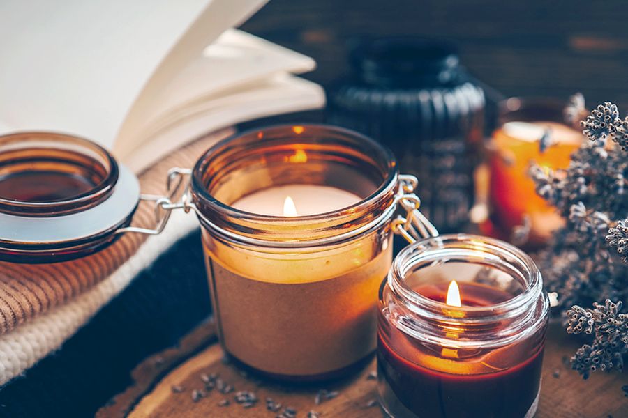 A couple of lit candles sit next to a sprig of flowers, illustrating how candles add to a cosy autumn atmosphere in Photobox's hygge decor tips.