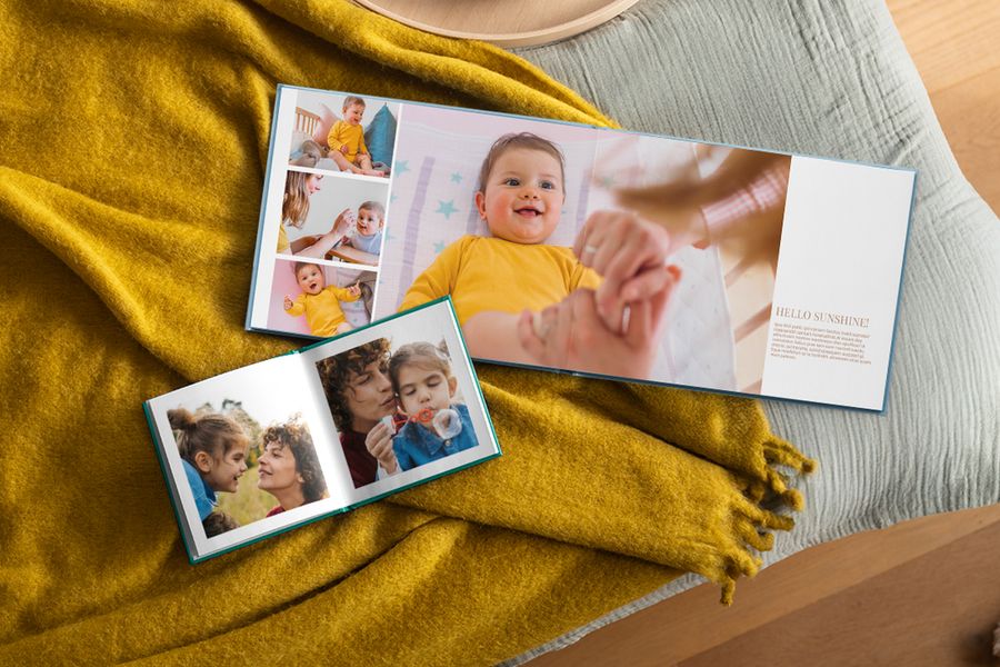 Two personalised photo books lie open showing family photos, resting on a mustard yellow throw, illustrating how Photobox photo books fit into a hygge home.