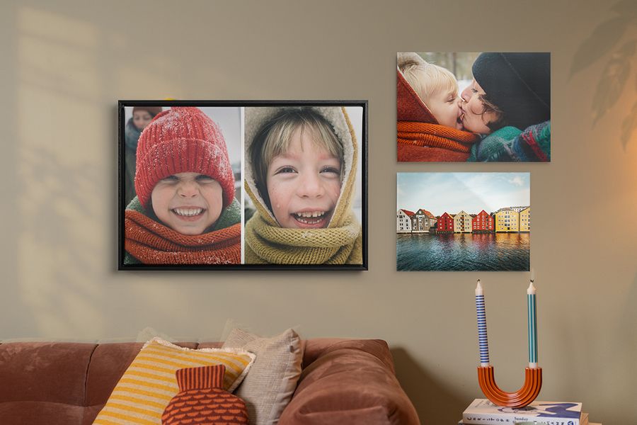 Three examples of personalised wall art hang above a sofa in a living room, autumnal family prints featuring smiling kids in winter gear, illustrating how Photobox wall art adds cosy hygge style to your home.