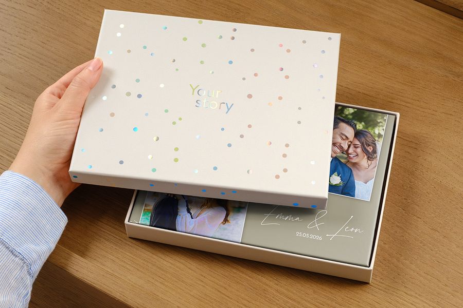 A wedding photo book sits inside the new presentation box, its cover showing a picture of the couple and the wedding date as the title, partially obscured by the ajar gift box lid, illustrating how a presentation box is worth it for a premium wedding album.