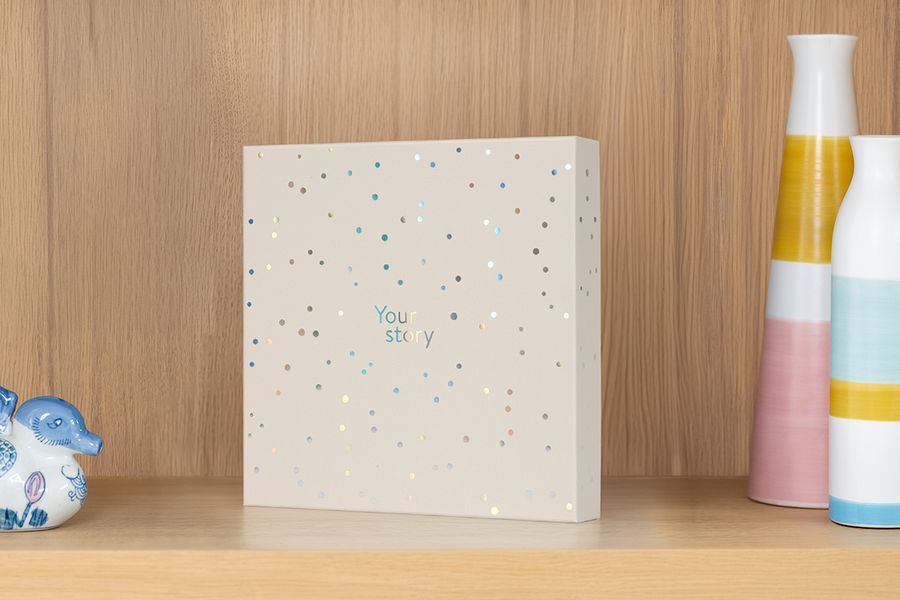 The presentation box sits on a shelf next to a vase and trinkets, illustrating how it doubles as an attractive photo album storage box.