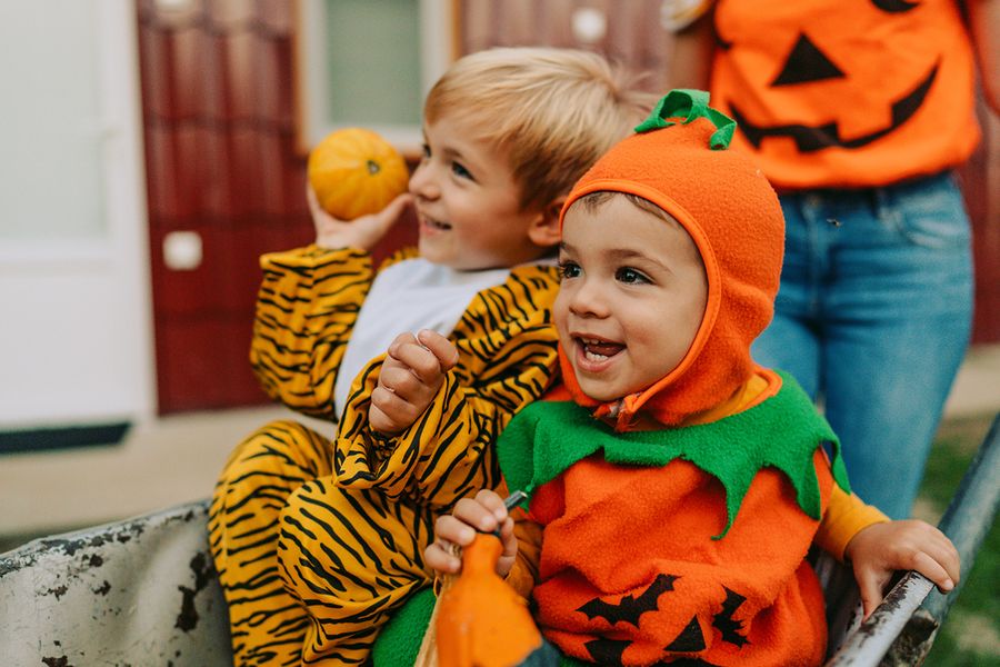 Two kids in Halloween fancy dress, one dressed as a pumpkin and one as a tiger, illustrating Photobox's sweet and cute Halloween quotes for Instagram.