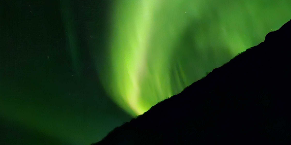 Very green northern lights across the night sky, illustrating Photobox’s tips on how to photograph the northern lights and aurora borealis.