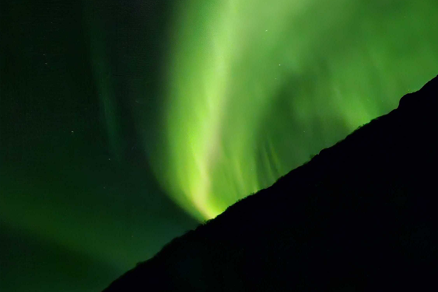 Very green northern lights in the sky, illustrating Photobox’s composition tips for photographing aurora borealis.