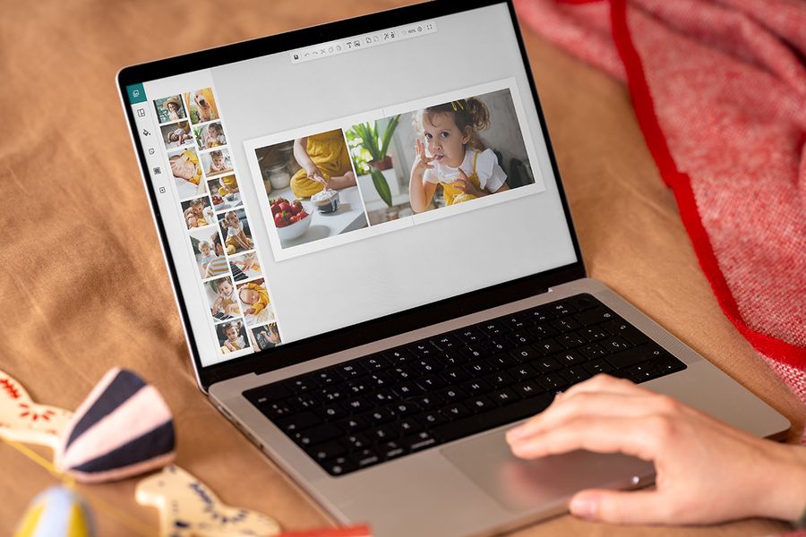 Hands at a laptop showing Photobox’s online editor, demonstrating how easy it is to make a photo book as a personalised Christmas gift, illustrating Photobox’s timeline for creating a personalised photo gift.
