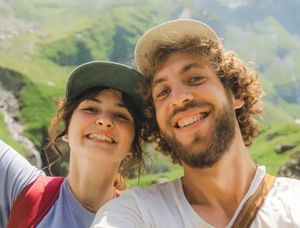 A smiling couple in a scenic hilly landscape enjoying a summer adventure, perfect for finding summer photo captions for Instagram or a Photobox photo book.