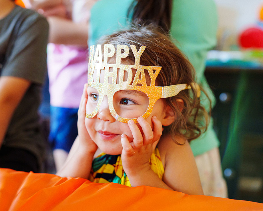 Little girl wearing a golden "Happy birthday" face mask.