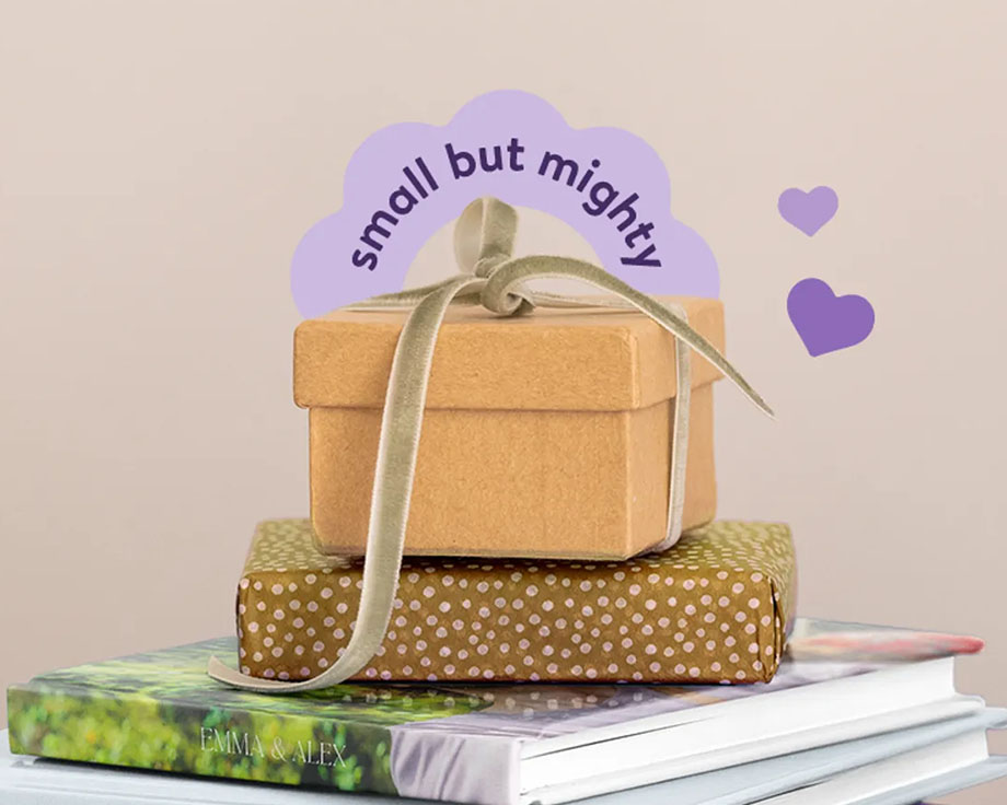 A pile of photo books and wrapped presents, with a little box on top of it saying "Small but mighty".