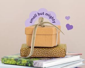 A stack of Photobox photo books with a wrapped present on top, inspiring personalised small gifts and thoughtful photo gift ideas.