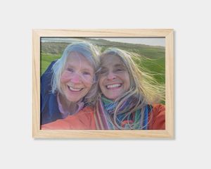 A framed poster featuring an image of two women smiling