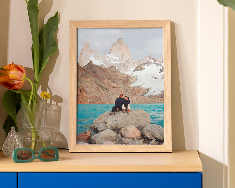 Framed landscape photo leaning on a wooden shelf