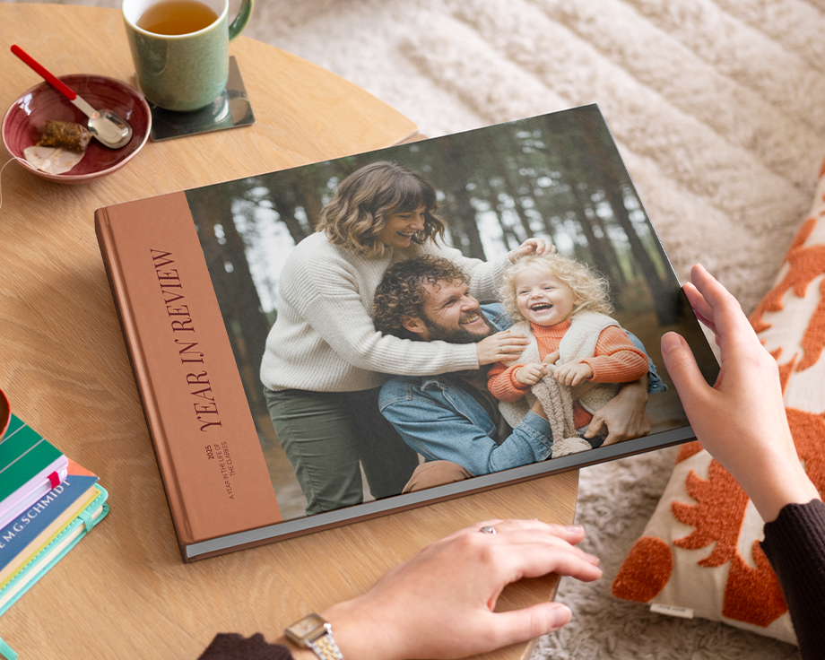 A year in review Photobox coffee table photo book with an attractive family photo on the cover, displayed on a coffee table as inspiration for a custom coffee table book.