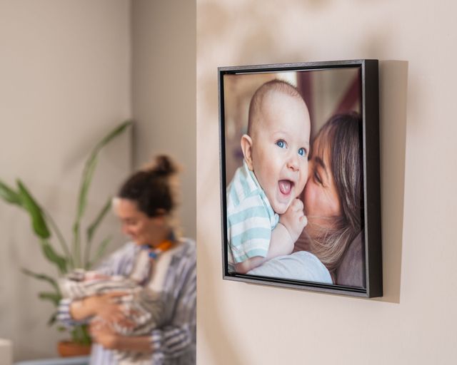 Framed canvas print featuring a mum cuddling her baby, displayed on a wall
