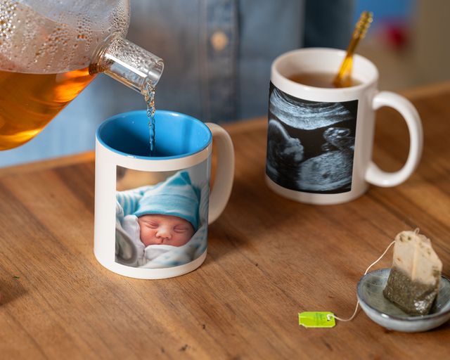 Tea poured into a personalised photo mug with a newborn picture beside an ultrasound scan mug.