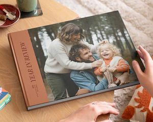 A year in review Photobox coffee table photo book with an attractive family photo on the cover, displayed on a coffee table as inspiration for a custom coffee table book.