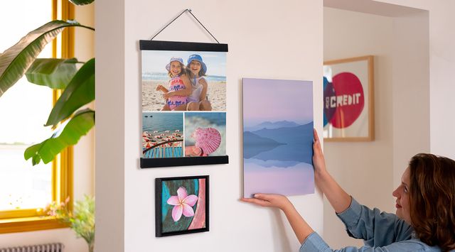 Person hanging a print next to two framed prints